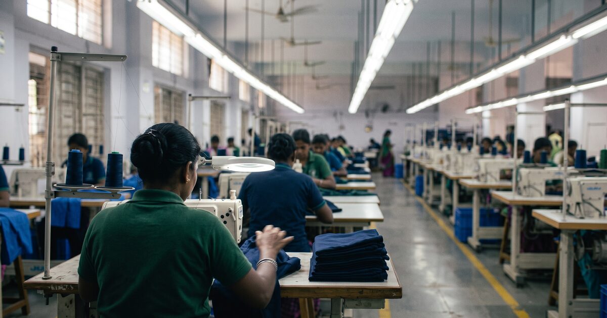 Operator at a sewing machine with the production line receding into the background